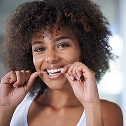 woman flossing to prevent dental emergencies in Calimesa 