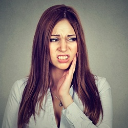 A woman holding her cheek in pain