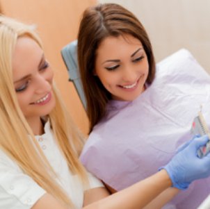 Assistant and dental patient looking at tooth color chart