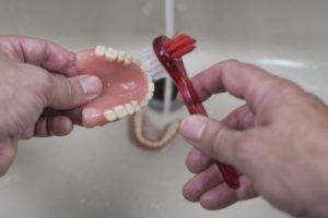 person cleaning their dentures