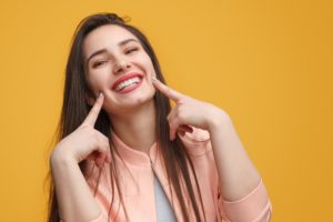 Woman pointing to her attractive smile from cosmetic dentist.