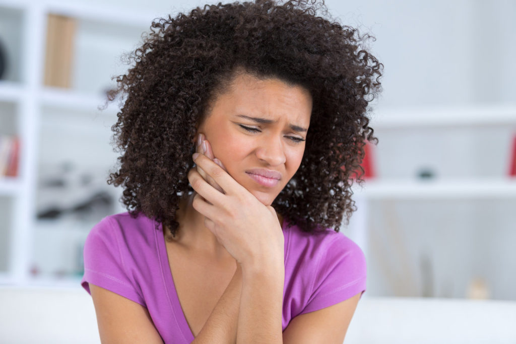 Woman in pain considers visiting an emergency dentist.