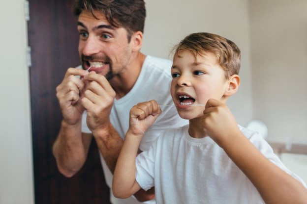 Father teaching his son how to floss.