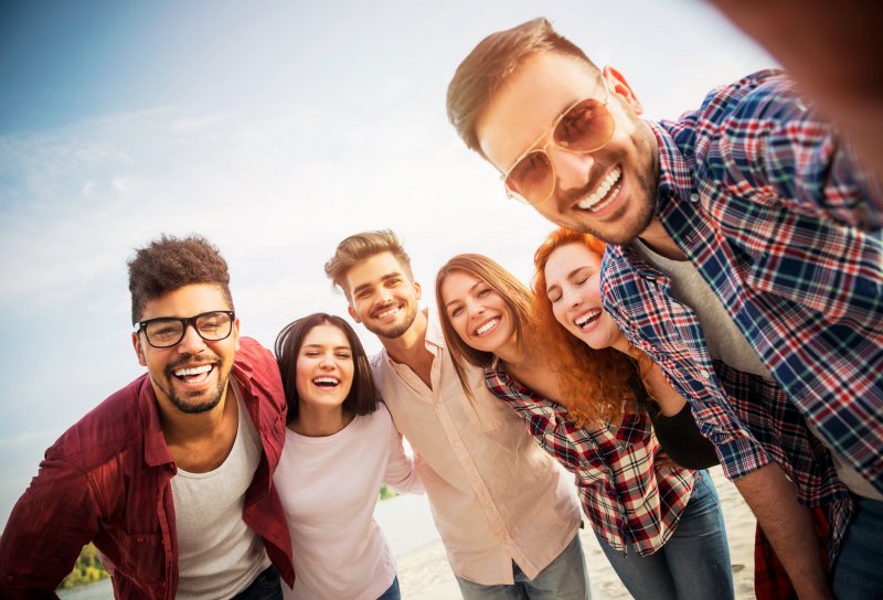 Patient smiling with friends after getting dental implants